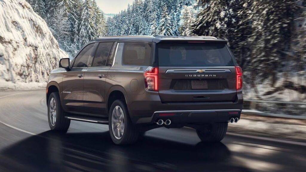 2023 Chevrolet Suburban rear view showing full-width LED taillights, power liftgate with extended opening, cavernous cargo area, dual exhaust outlets, and substantial extended overhang