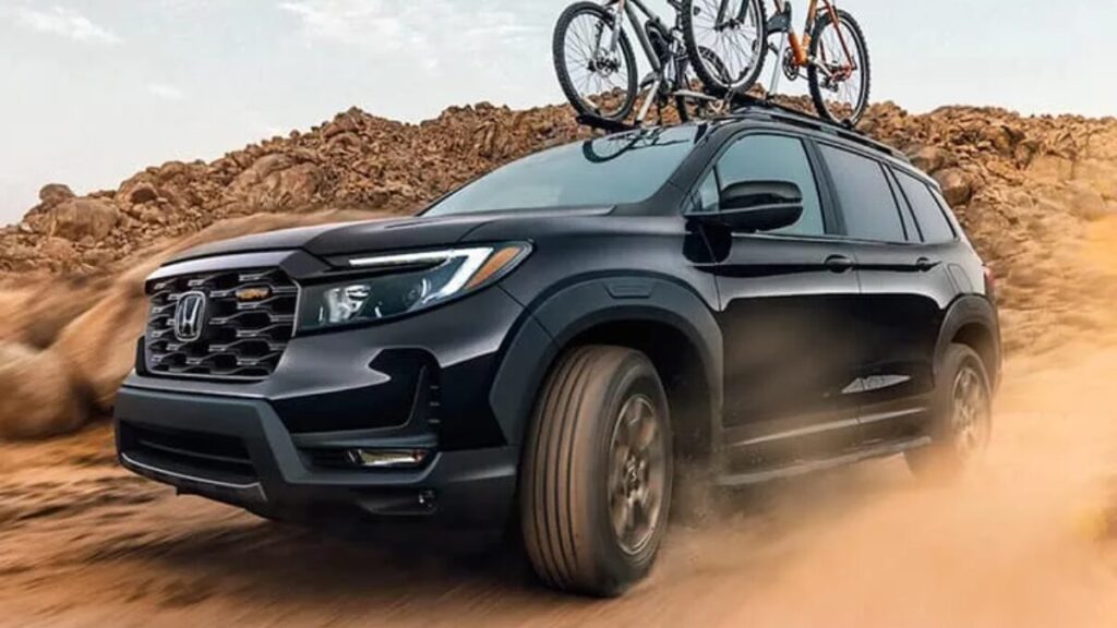 2023 Honda Passport TrailSport driving on a dirt trail with all-terrain tires and rugged off-road styling