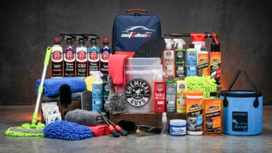 Car wash kit supplies including a bucket, microfiber mitt, brushes, and detailing bottles arranged beside a clean vehicle
